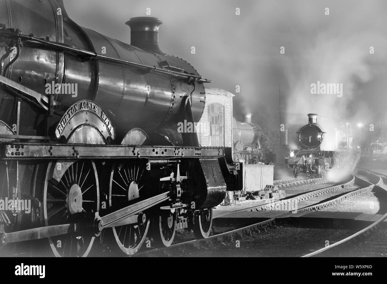 Ricreazione nostalgica di una scena del capannone ferroviario dell'era del vapore, in bianco e nero, enfatizzando i giorni passati della gloria. Foto Stock