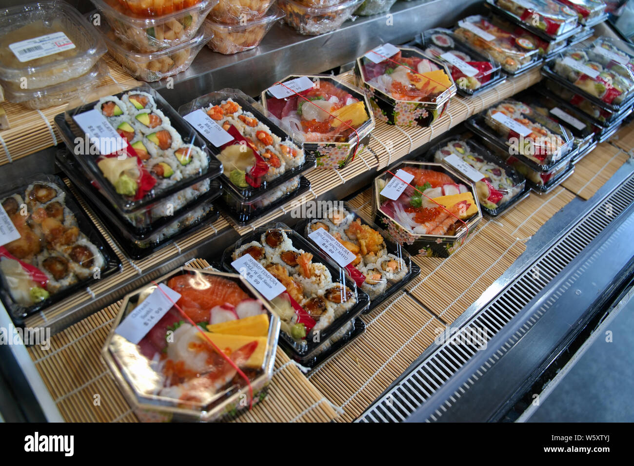 Vetrina refrigerata di allettanti piatti sushi e tempura roll bento boxes. Foto Stock