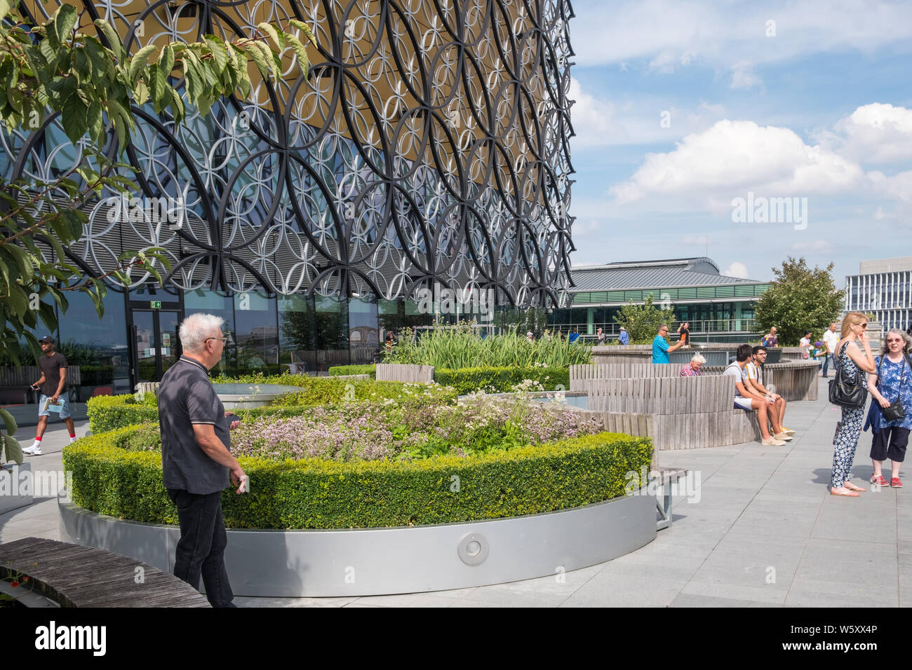 Visitatori godendo un sole estivo sulla biblioteca di Birmingham roof garden Foto Stock