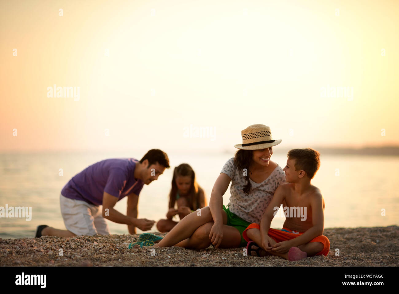 La famiglia felice rilassante sulla spiaggia al tramonto. Foto Stock