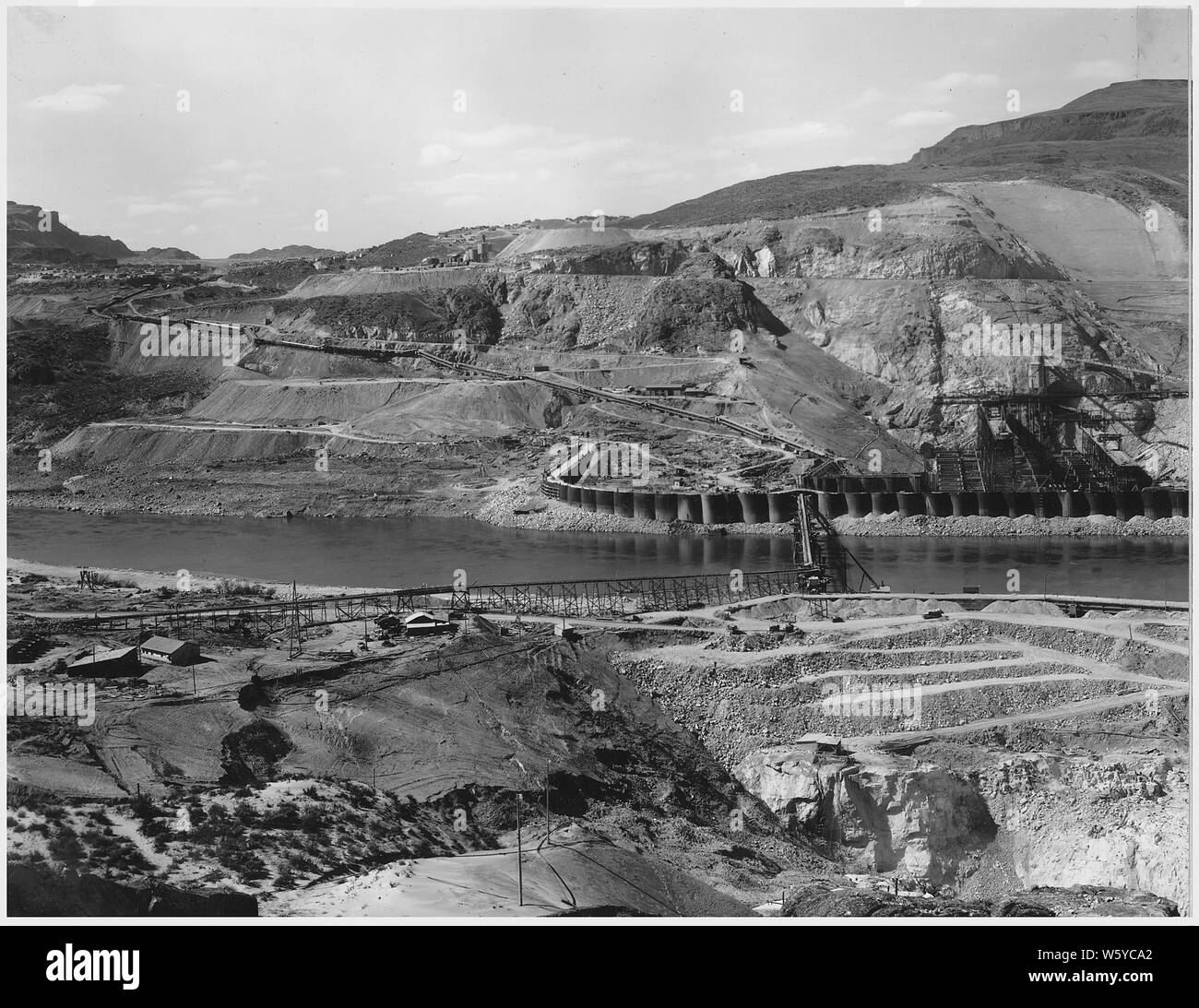 Tre-vista panoramica dalla cima del riscontro est . Il calcestruzzo Eastmix impianto in costruzione nel centro compare in primo piano.; Portata e contenuto: fotografia dal volume due di una serie di album di foto per documentare la costruzione del Grand Coulee Dam e i relativi lavori sul bacino di Columbia progetto. Note generali: Questa immagine è parte di una vista panoramica che include voci 1007, 1007, e 1007-B. L'immagine originale misura circa 28 cm di larghezza. Foto Stock