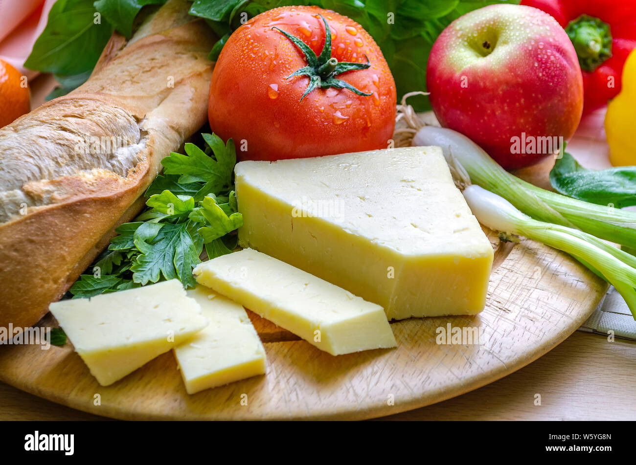 Un colpo orizzontale di un delizioso spuntino veloce di un plowman pranzo con pane francese di formaggio maturo un pomodoro fresco e un apple. Foto Stock