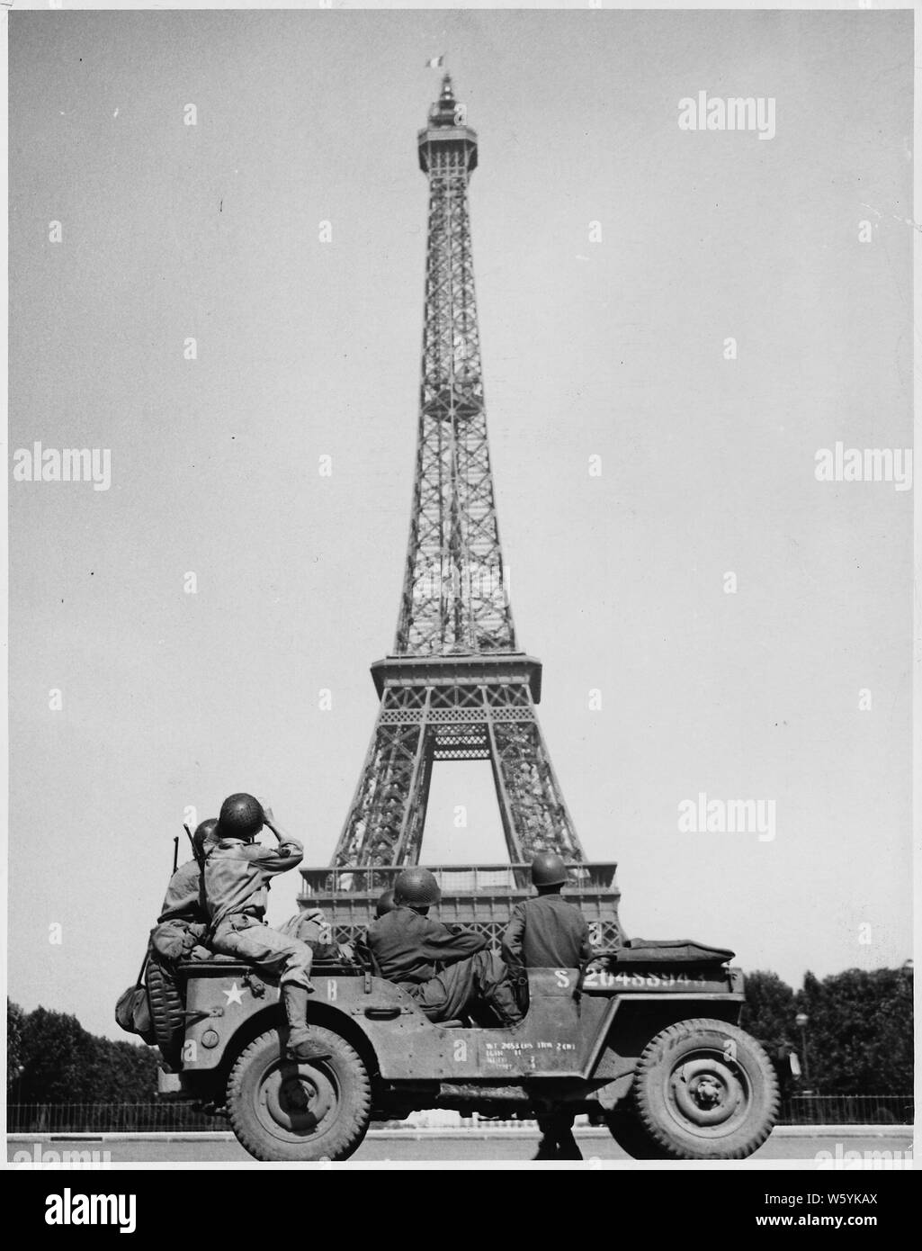 Durante la Seconda guerra mondiale: Europa: Francia; soldati americani guarda come il tricolore vola da la Torre Eiffel di nuovo Foto Stock