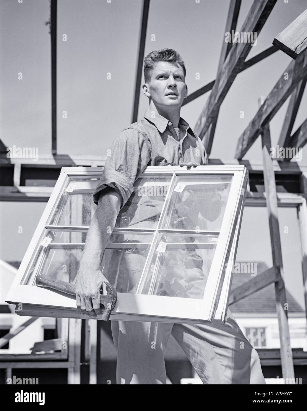 1940s uomo lavoratore edile falegname vetraio su HOUSE BUILDING SITE TRASPORTARE IL LEGNO E VETRO SERRAMENTI E MARTELLO - b18736 HAR001 HARS a mezza lunghezza fisica delle persone maschi residenziale edifici professione fiducia B&W libertà successo abilità Competenze occupazione FORZA IL SERVIZIO CLIENTI E LA RIMOZIONE DI CARRIERE KNOWLEDGE basso angolo corso orgoglio sulle autorità case occupazioni riquadri concettuale di residenza responsabile elegante esperto MID-adulto metà uomo adulto soluzioni SASH TRADESMAN IN BIANCO E NERO di etnia caucasica HAR001 Installazione di vecchio stile Foto Stock