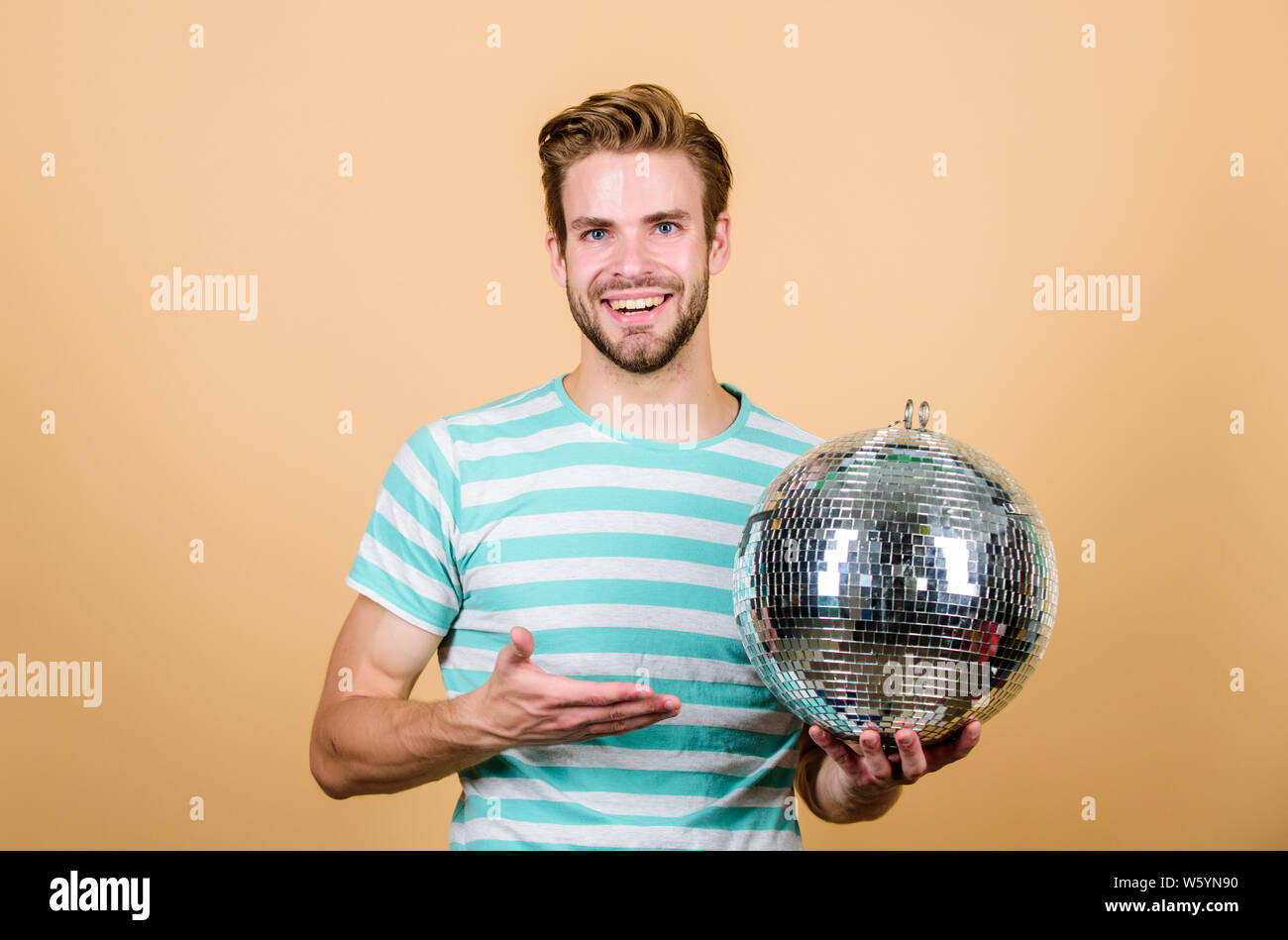 Allegro dj uomo. Uomo bello tenere palla da discoteca. Danze da discoteca night club. Musica retrò. Ragazzo che vi invitano a parte. Migliaia di minuscoli specchi che riflettono la creazione delle luci di atmosfera da discoteca. Come circa la parte. Foto Stock