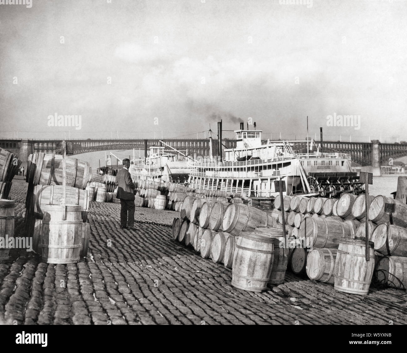 Argine circa 1900 barili DI MELE DA CALHOUN COUNTY ILLINOIS SPEDITI DA STEAMBOAT EADS BRIDGE IN BACKGROUND ST. LOUIS MO USA - Q75026 CPC001 HARS fiume Mississippi MO in vecchio stile pedalo' ST LOUIS STEAMBOAT Foto Stock