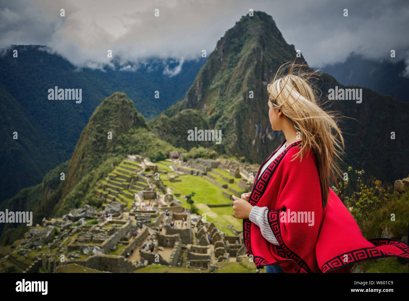 Donna turistiche traveler con il vestito rosso contemplando il Machu Picchu in Cusco, Perù Foto Stock