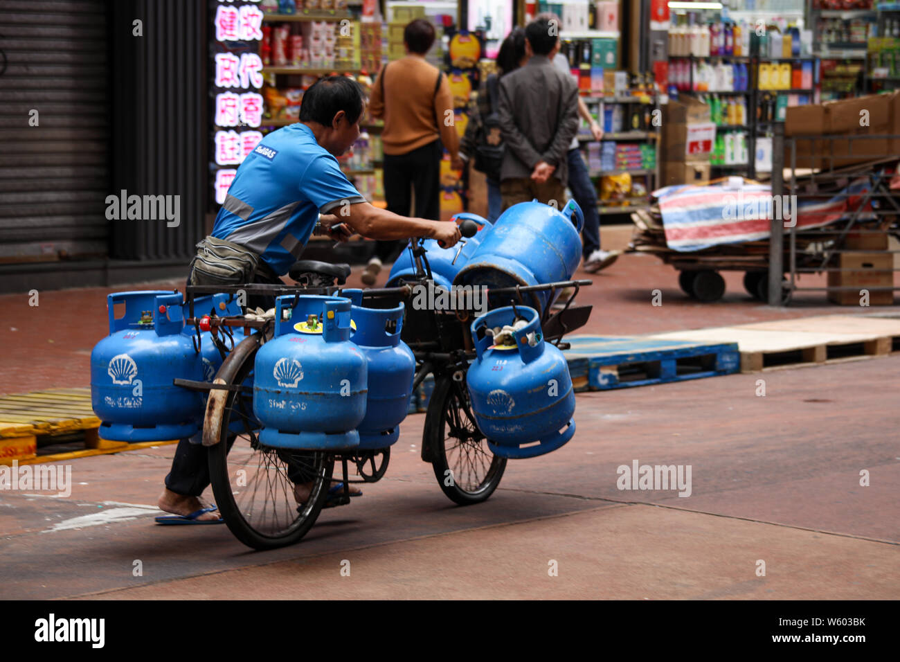 Uomo di mezza età che fornisce gas con bicicletta a Mong Kok, Hong Kong Foto Stock