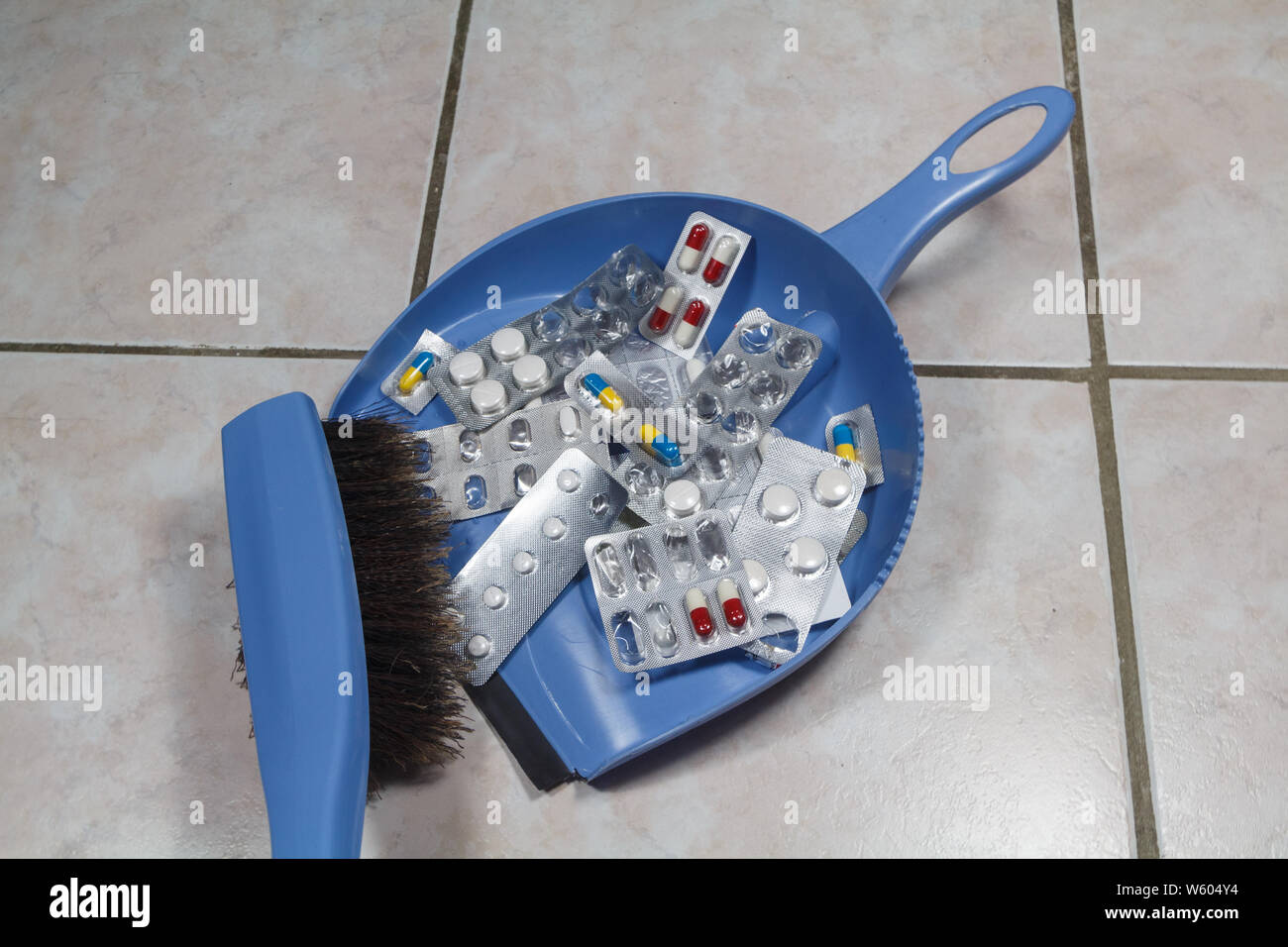 Gettare via le vecchie confezioni di pillole con un pennello e una paletta Foto Stock