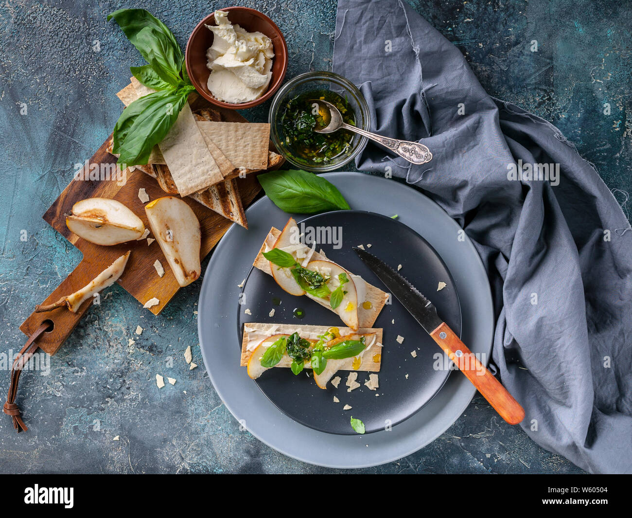 Biscotti Frollini con crema di formaggio e fette di pere. Hot Salsa con aglio e basilico. Vista superiore Foto Stock