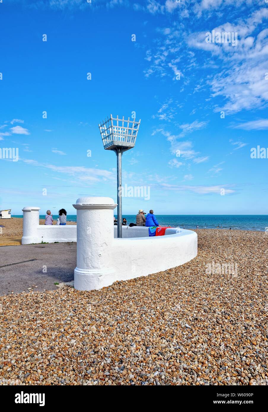 Il segnale di ferro faro sulla spiaggia a Bognor Regis con gente seduta sulla parete circostante,West Sussex England Regno Unito Foto Stock