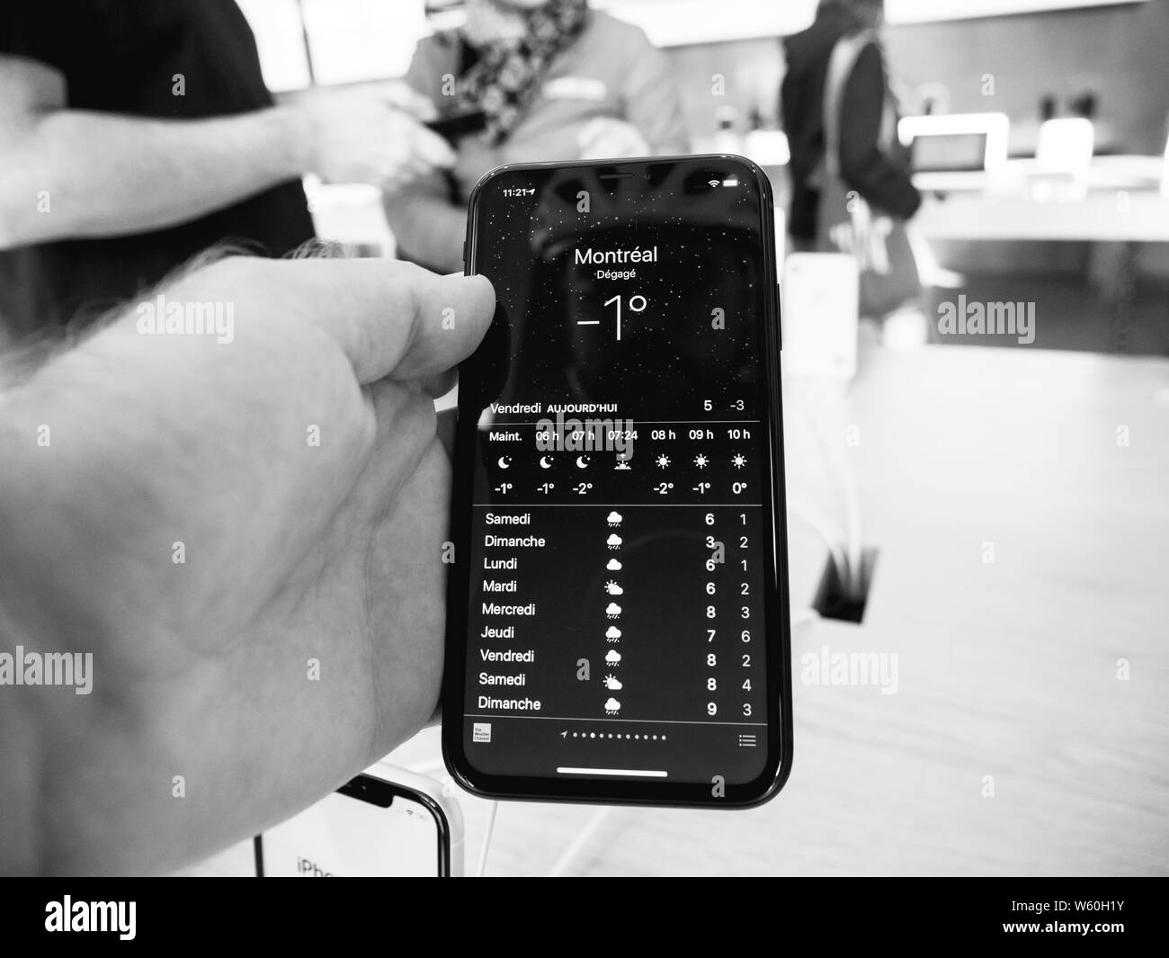 Parigi, Francia - Ott 26, 2018: Man mano che tiene iPhone più recente XR smartphone durante il giorno del lancio è fabbricato da Apple Computer ammirando app meteo con Montreal condizioni meteorologiche attuali Foto Stock