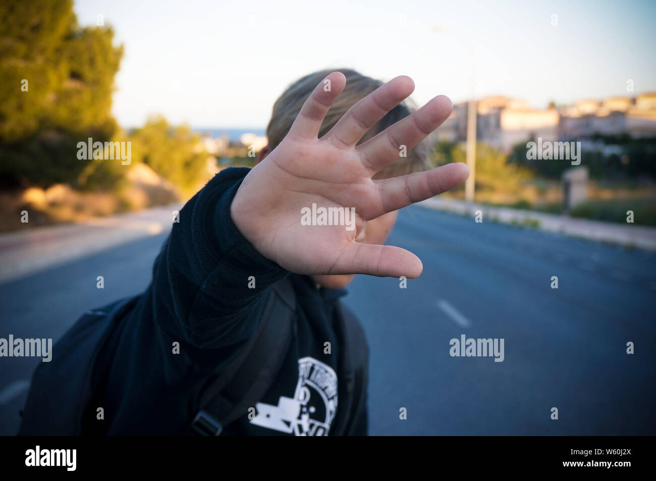 Adolescente nasconde il suo volto con palm su strada asfaltata Foto Stock