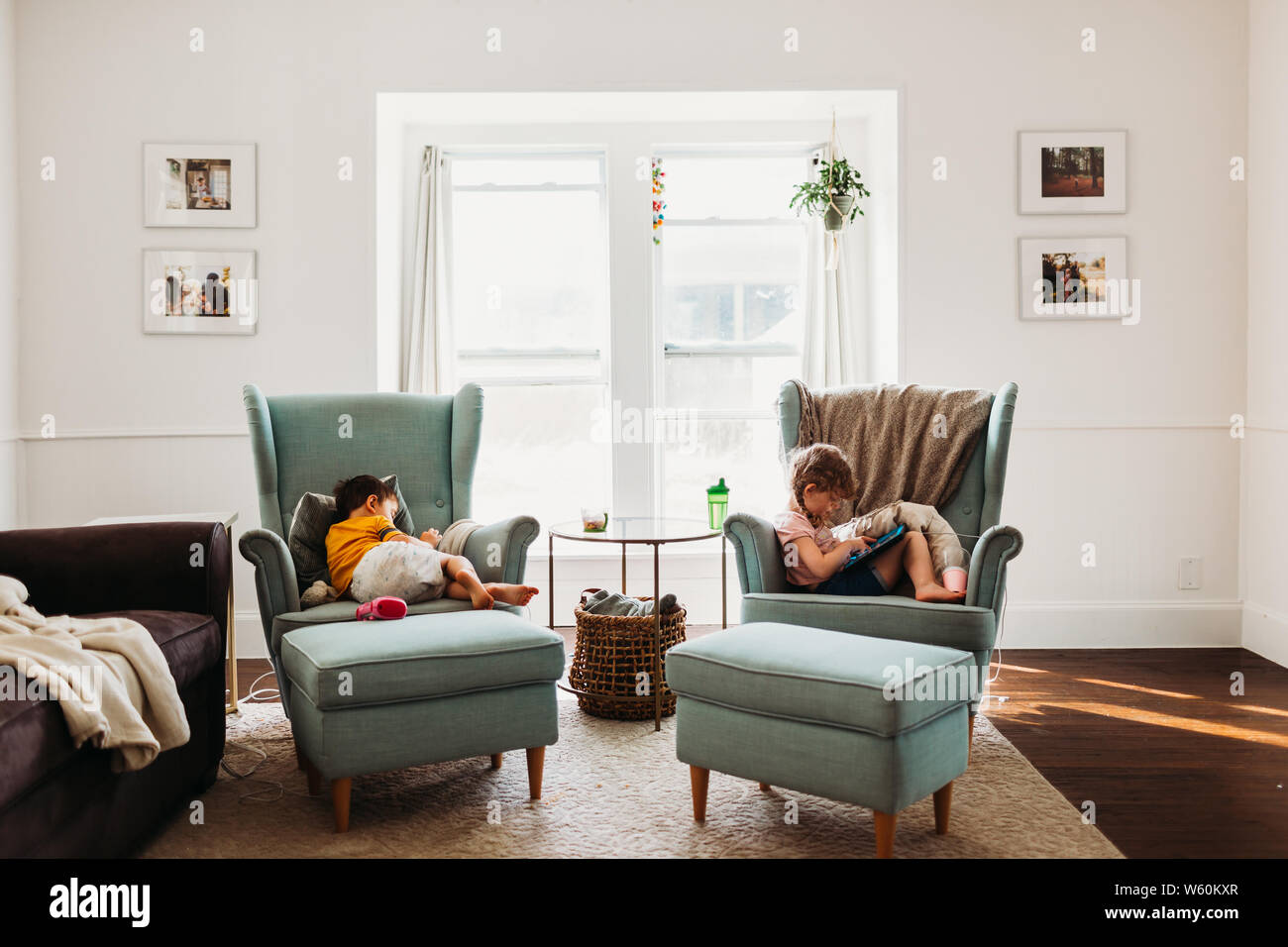 Ragazzo e ragazza di riposo in salotto utilizzando compresse Foto Stock