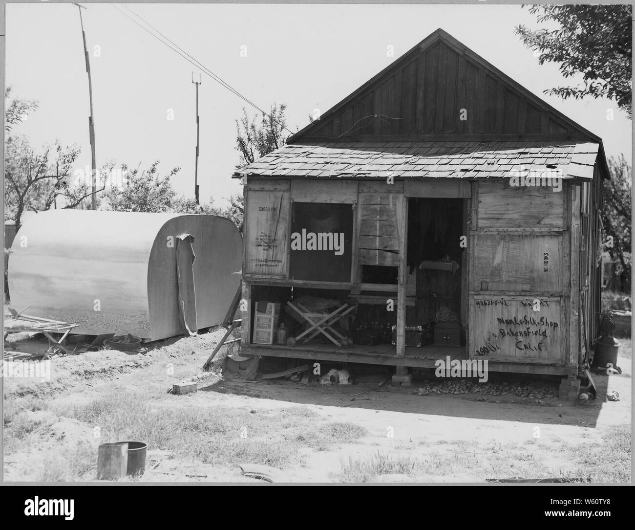 Arvin, Kern County, California. In una comunità di baracche in suddiviso orchard affittato a agricul . . .; Portata e contenuto: Full didascalia recita come segue: Arvin, Kern County, California. In una comunità di baracche in suddiviso orchard affittato per i lavoratori agricoli come case permanenti. Lavoratori on e off a rilievo. Baracche affitto da $7 a $12 al mese. No acqua corrente. Nota il rimorchio essendo costruito e patate memorizzati sotto casa. Abbattimenti probabilmente portato a casa dal lavoro nei campi di patate. Foto Stock