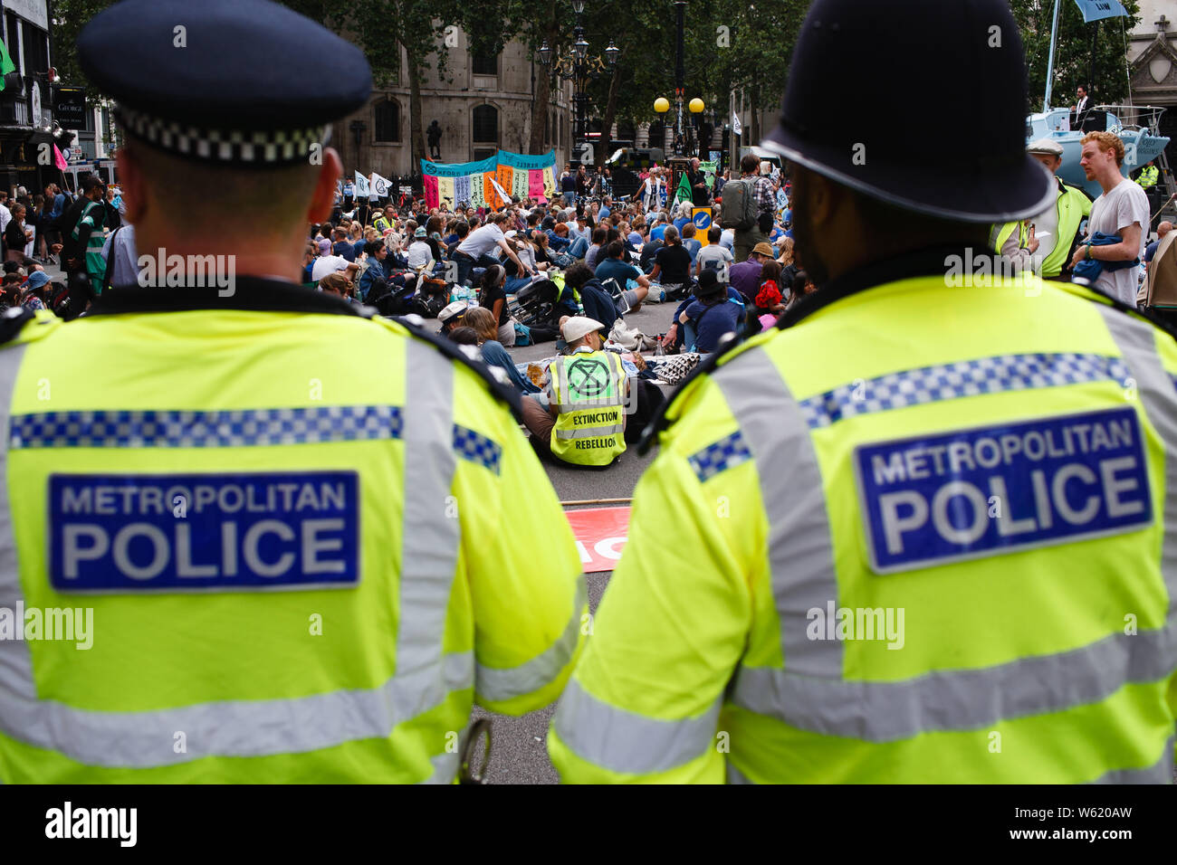 Luglio 15, 2019, London, Regno Unito: poliziotti vegliare come membri e sostenitori del cambiamento climatico gruppo attivista estinzione della ribellione prendere parte nella giornata di apertura del gruppo 'Summer Uprising' dimostrazione al di fuori della Royal Courts of Justice di Londra. Le dimostrazioni sono state anche tenutosi a Bristol, Cardiff, Leeds e Glasgow. Tra le loro richieste per una maggiore azione sul cambiamento climatico, manifestanti chiedono 'ecocide' (cioè la distruzione degli ecosistemi) per essere fatto un atto criminale. Il fulcro della protesta di Londra, una barca blu, il 'Polly Higgins', è chiamato dopo il ritardo amb. Foto Stock