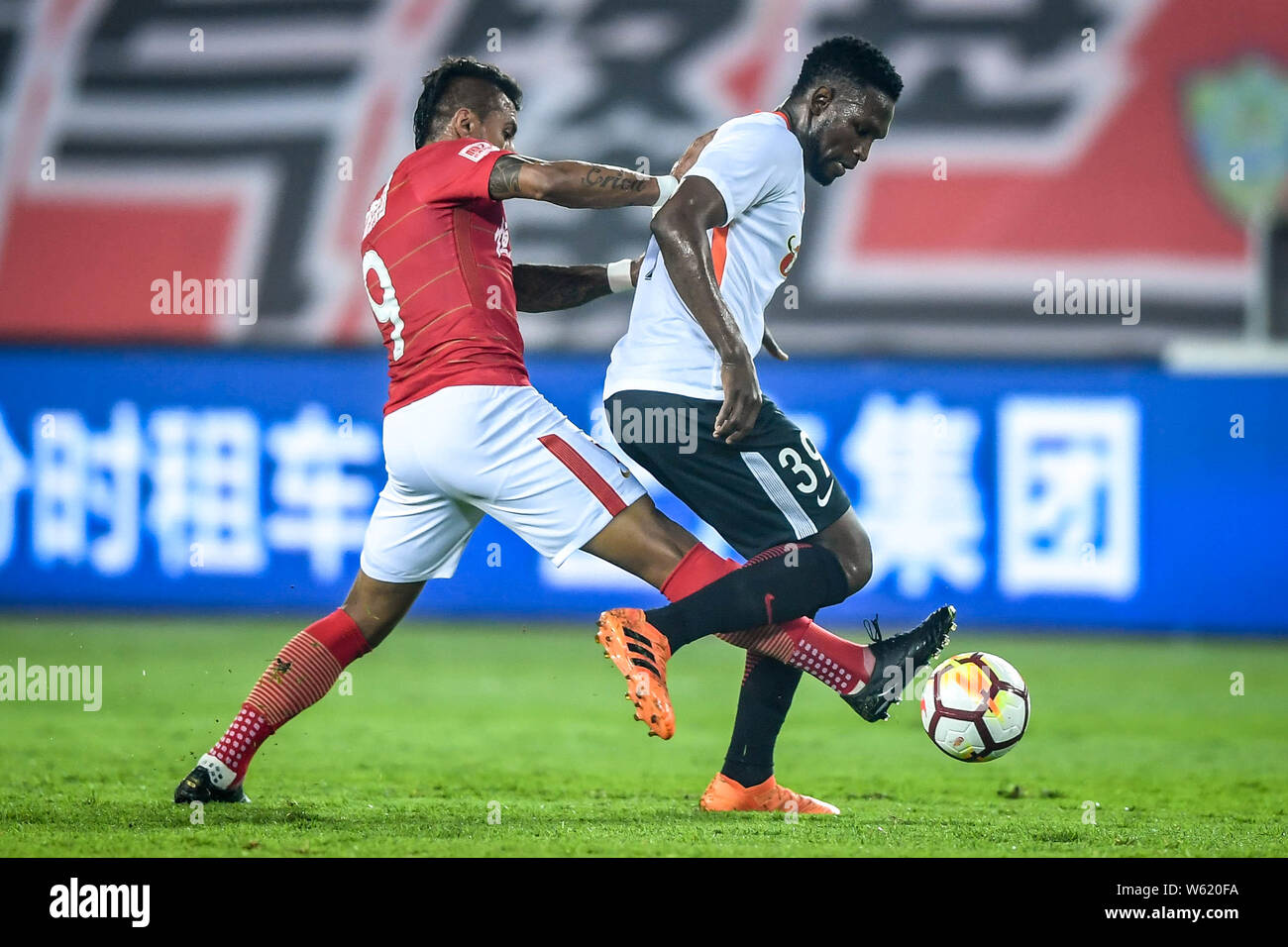 Il calcio brasiliano player Paulinho, sinistra, di Guangzhou Evergrande Taobao sfide di calcio senegalese player Makhete Diop di Pechino Renhe nella loro Foto Stock