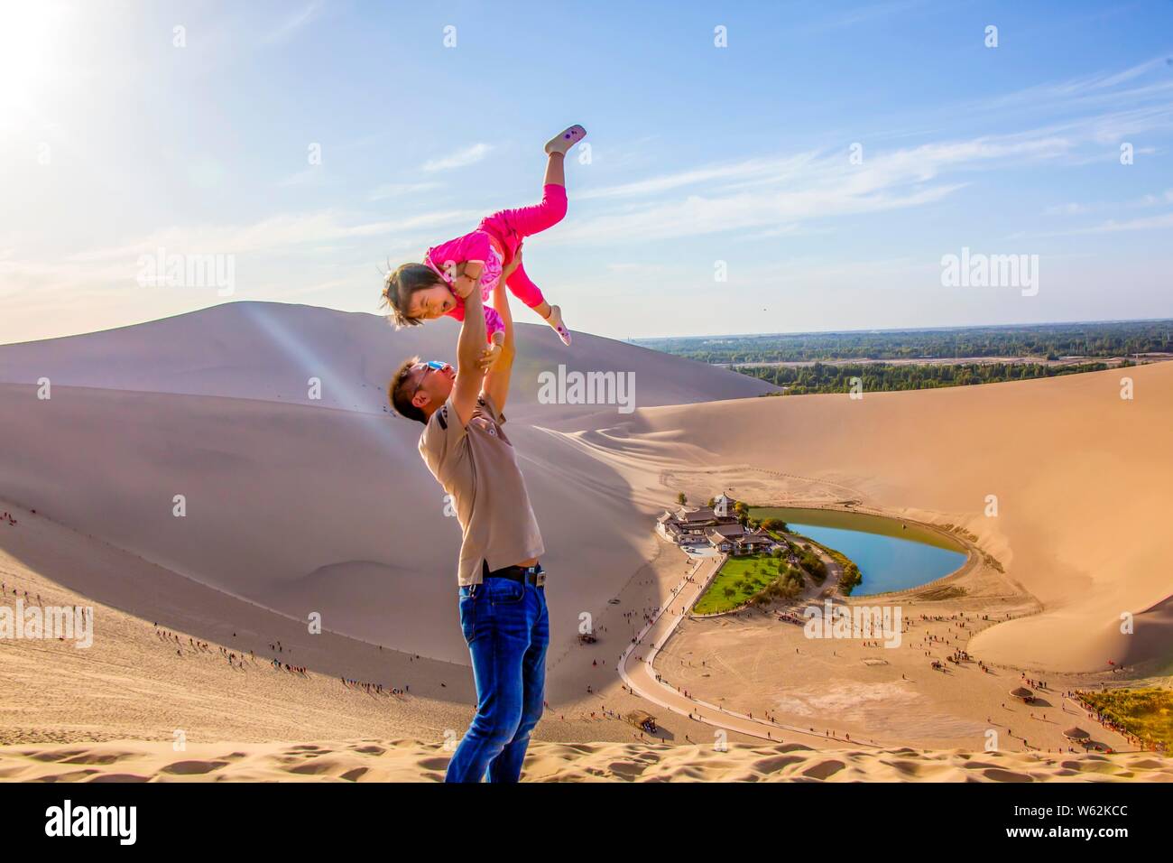 I turisti posano per foto vicino a mezzaluna Lago, noto anche come Yueyaquan, circondato da Singing-Sand dune nel deserto del Gobi in Dunhuang, n. Foto Stock