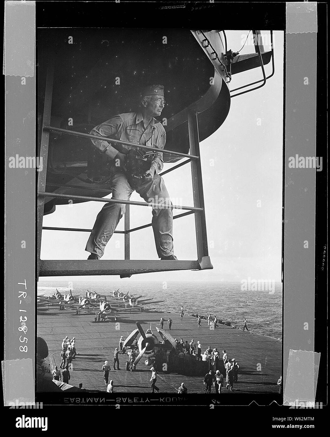 Il cap. Edward J. Steichen, USNR, (pensionati), Photographic Expert, sull' isola di piattaforma, studi i suoi dintorni per uno dei suoi eccezionali fotografie della vita a bordo di una portaerei. Il cap. Steichen tenutasi il rango di Comdr. In questo momento.; Note Generali: Utilizzo di guerra e di conflitto numero 759 quando si ordina una riproduzione o la richiesta di informazioni su questa immagine. Foto Stock