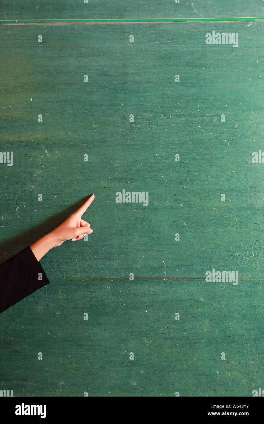 Giovane donna asiatica insegnante di puntamento a mano qualcosa sulla vecchia scheda verde Foto Stock