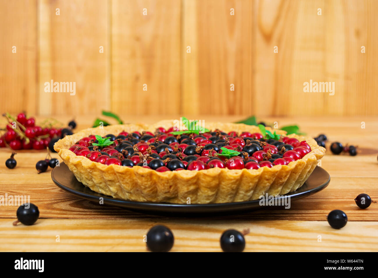 Deliziosa torta con crema pasticcera e ribes su sfondo di legno Foto Stock