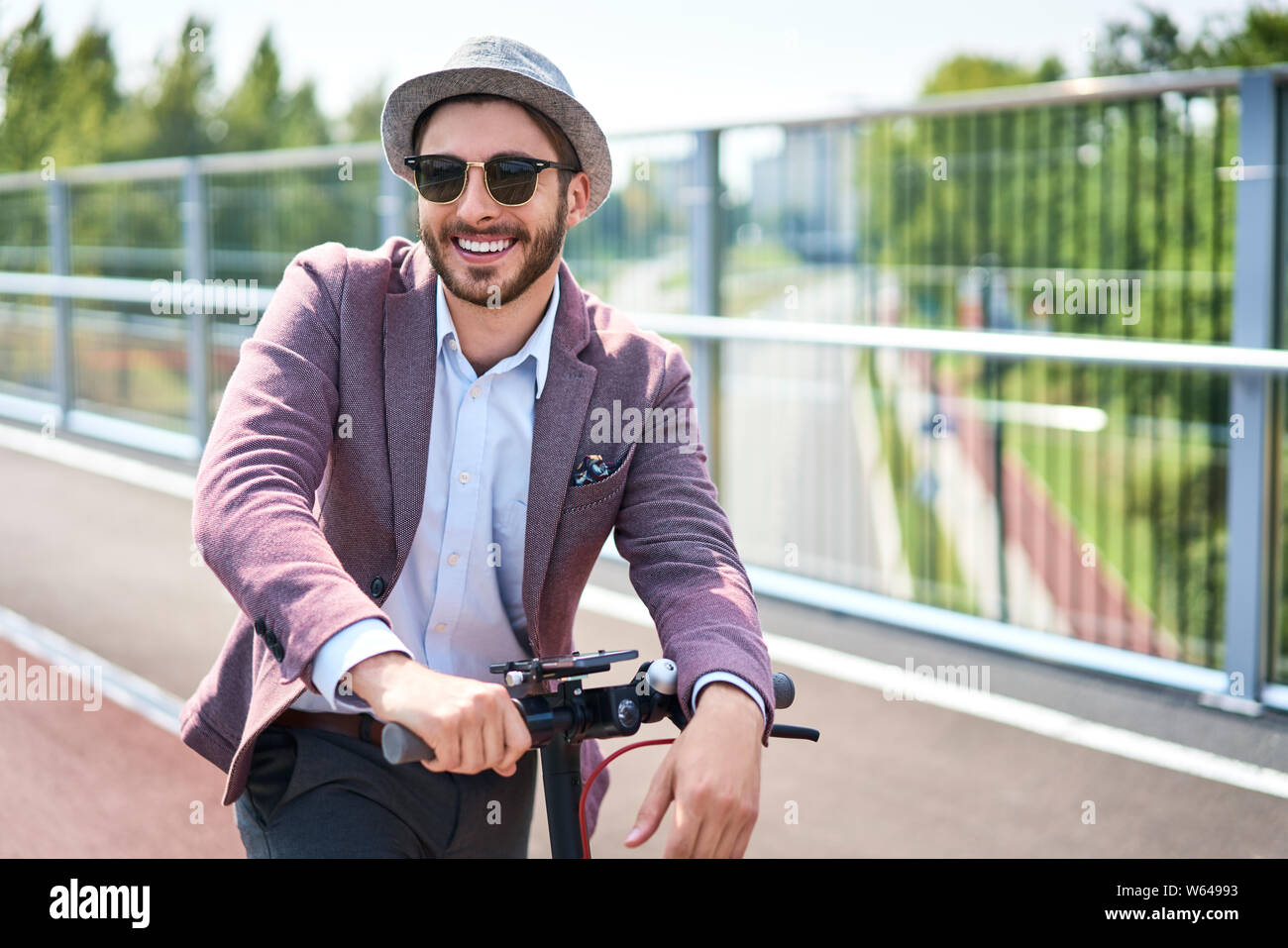 Ritratto di elegante uomo su scooter elettrico durante la giornata di sole Foto Stock