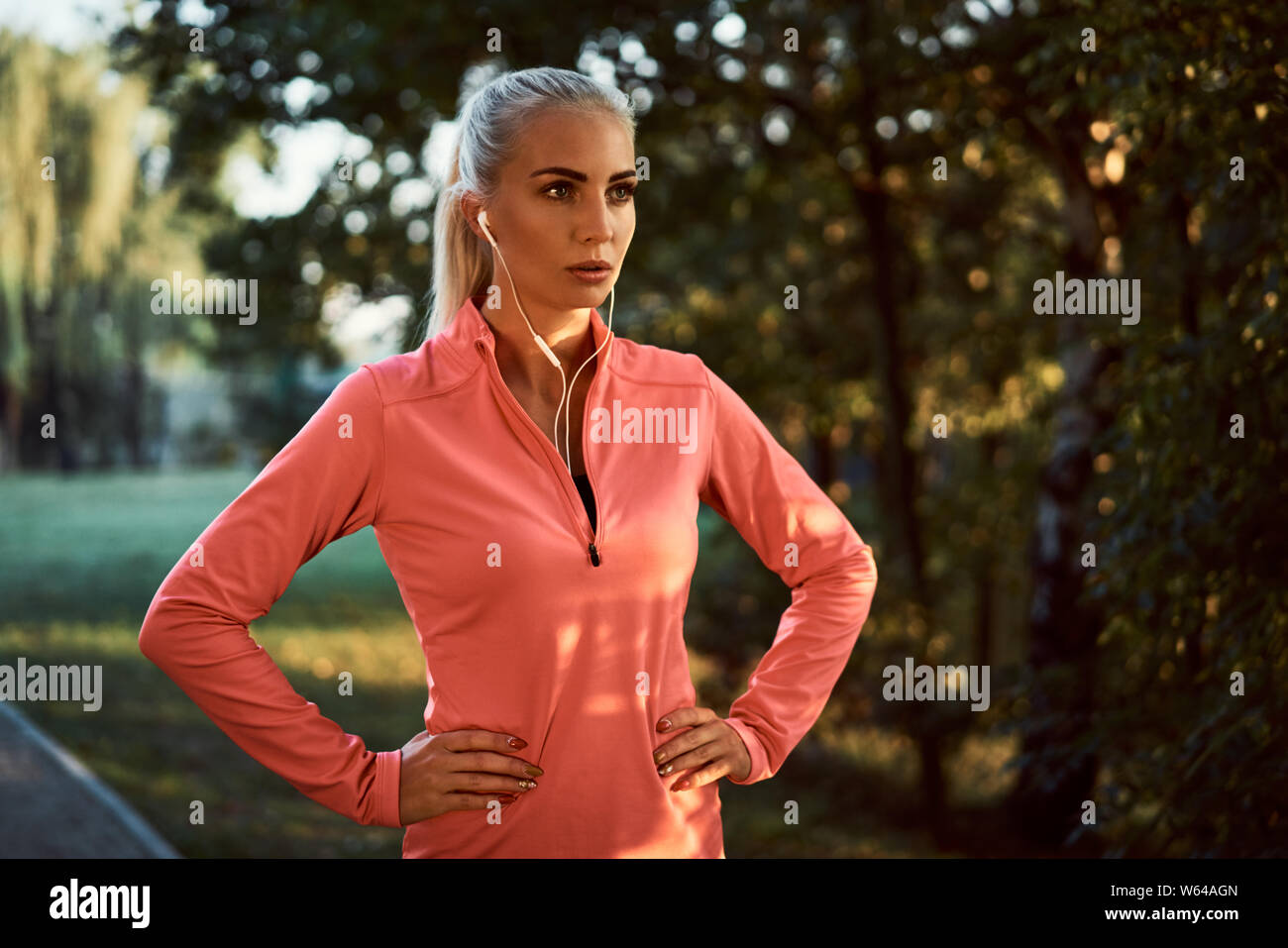 Ritratto di donna runner con cuffie in appoggio durante la ginnastica mattutina Foto Stock