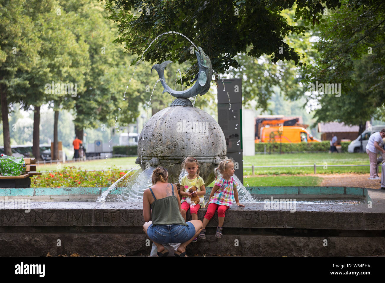 La madre e le figlie godendo di rimanere al fontana nella parte interna della città di Mainz, Germania Foto Stock