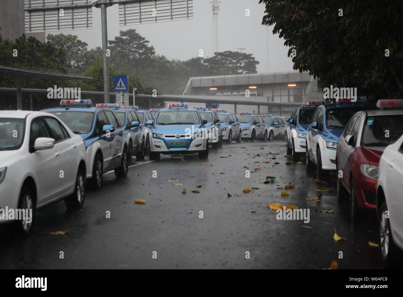 I taxi in coda fino a essere ricaricata in Pesanti rovesci di pioggia e forte vento causato dal tifone Mangkhut, la ventiduesima typhoon dell'anno, a fronte di un charing sta Foto Stock