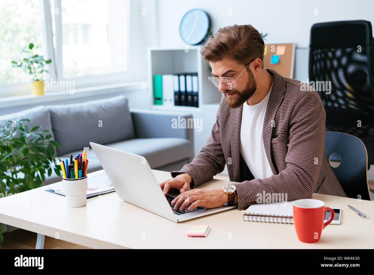 Giovane imprenditore di avvio funzionante sul computer portatile in modern home office. Ritratto di imprenditore durante il lavoro Foto Stock