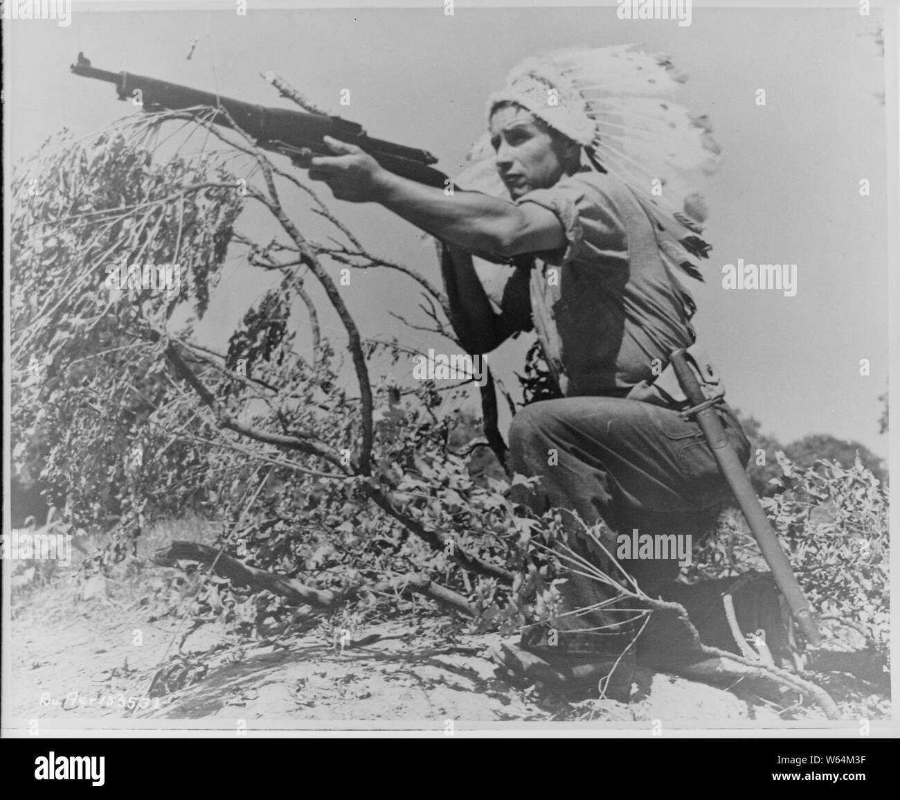 Dan Waupoose, un capo Menomini; full-length, inginocchiato con un fucile e indossando un copricapo piumato, Algeri, Lousiana, 08/24/1943 Foto Stock