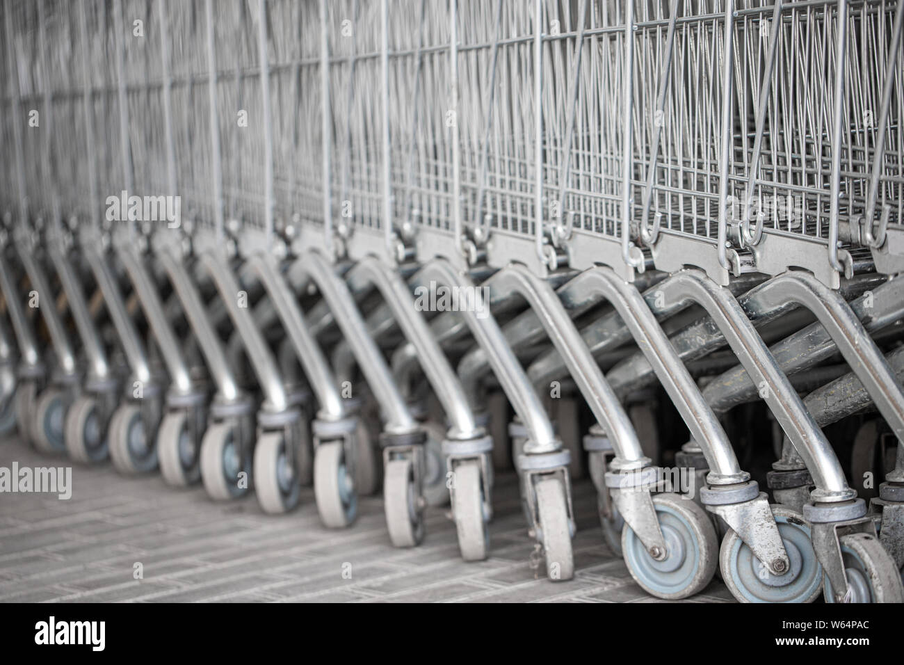Carrelli disposti in una fila sulla strada vicino al supermercato.Chiudere la ruota del carrello. Concetto di shopping. Messa a fuoco selettiva. Foto Stock