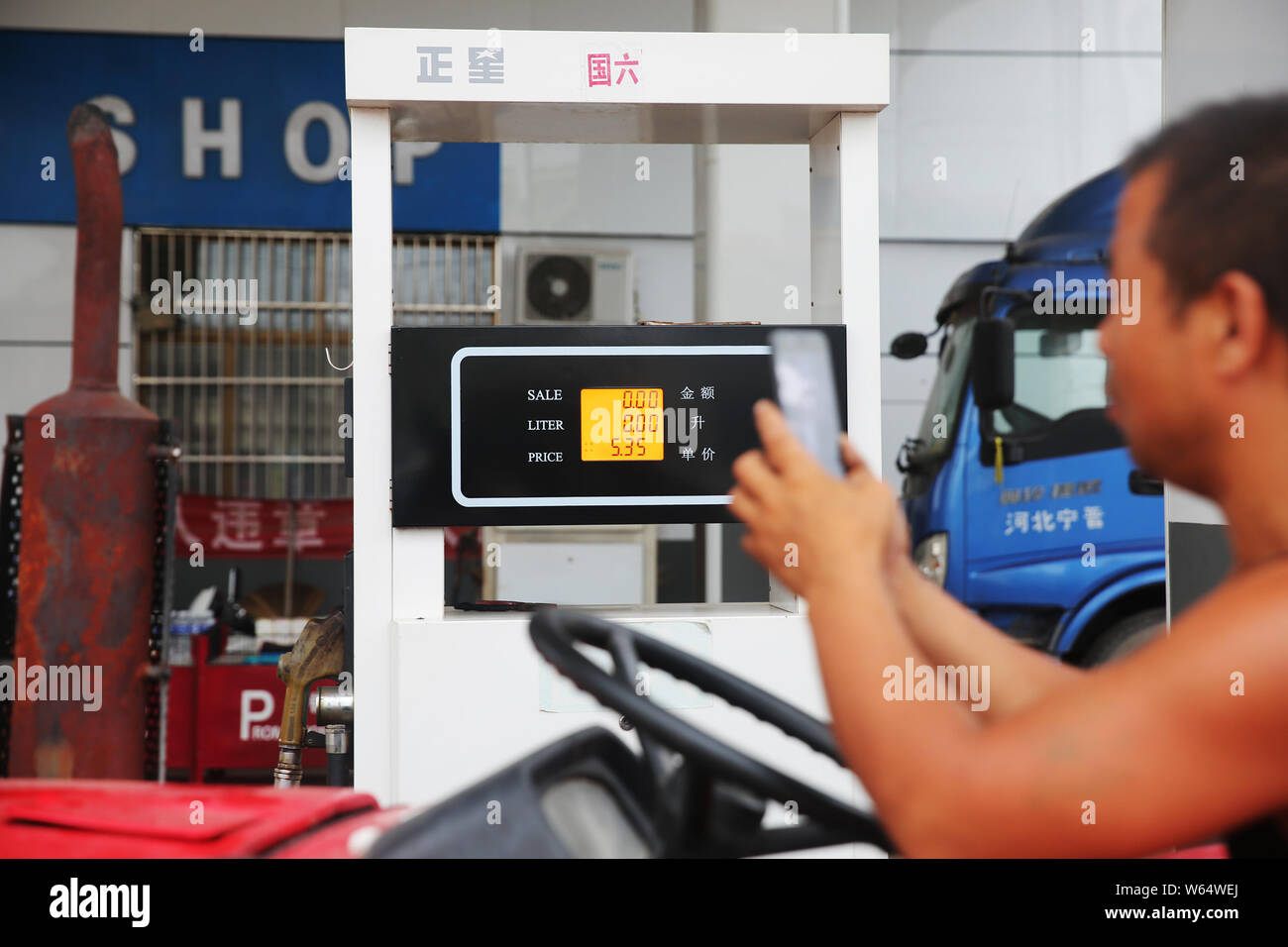 Padre cinese Liu Ningliang registra il prezzo del gasolio in una stazione di benzina come ha preso le sue due figlie per un mese di viaggio su un trattore da Sanya di Foto Stock