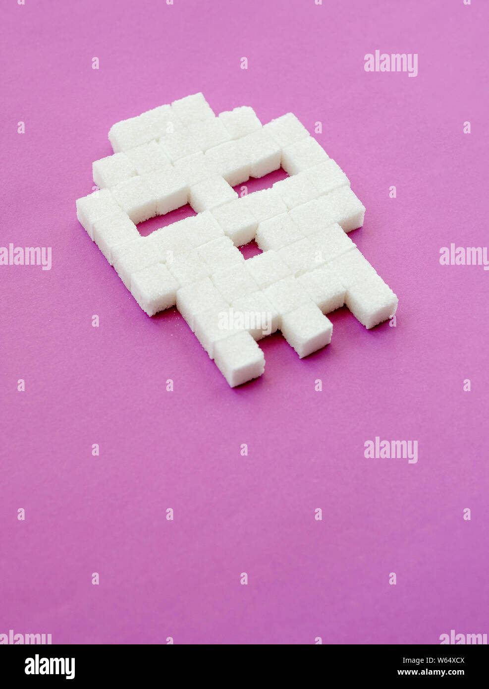 Zollette di zucchero stabilite in forma di teschio su sfondo viola. Lo  zucchero bianco è la morte. Il diabete, malattia di zucchero, alimenti  dannosi per la salute, la dieta concetto. Spazio di