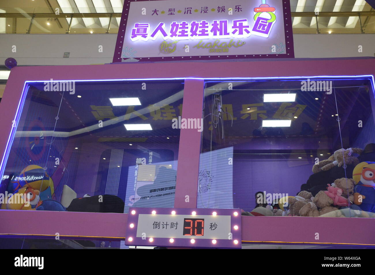 I giocatori grab bambole all'interno di un edificio a due piani bambola umana-grabbing macchina che è la Cina del primo dente umano macchina, ad un centro commerciale per lo shopping di Shanghai, Cina Foto Stock