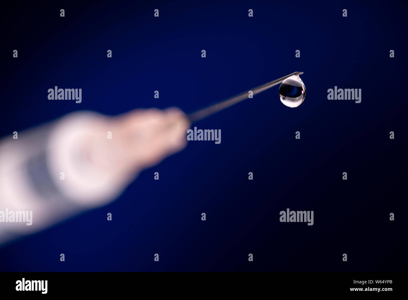 Primo piano di una cannula con drop e la siringa davanti a sfondo blu scuro Foto Stock