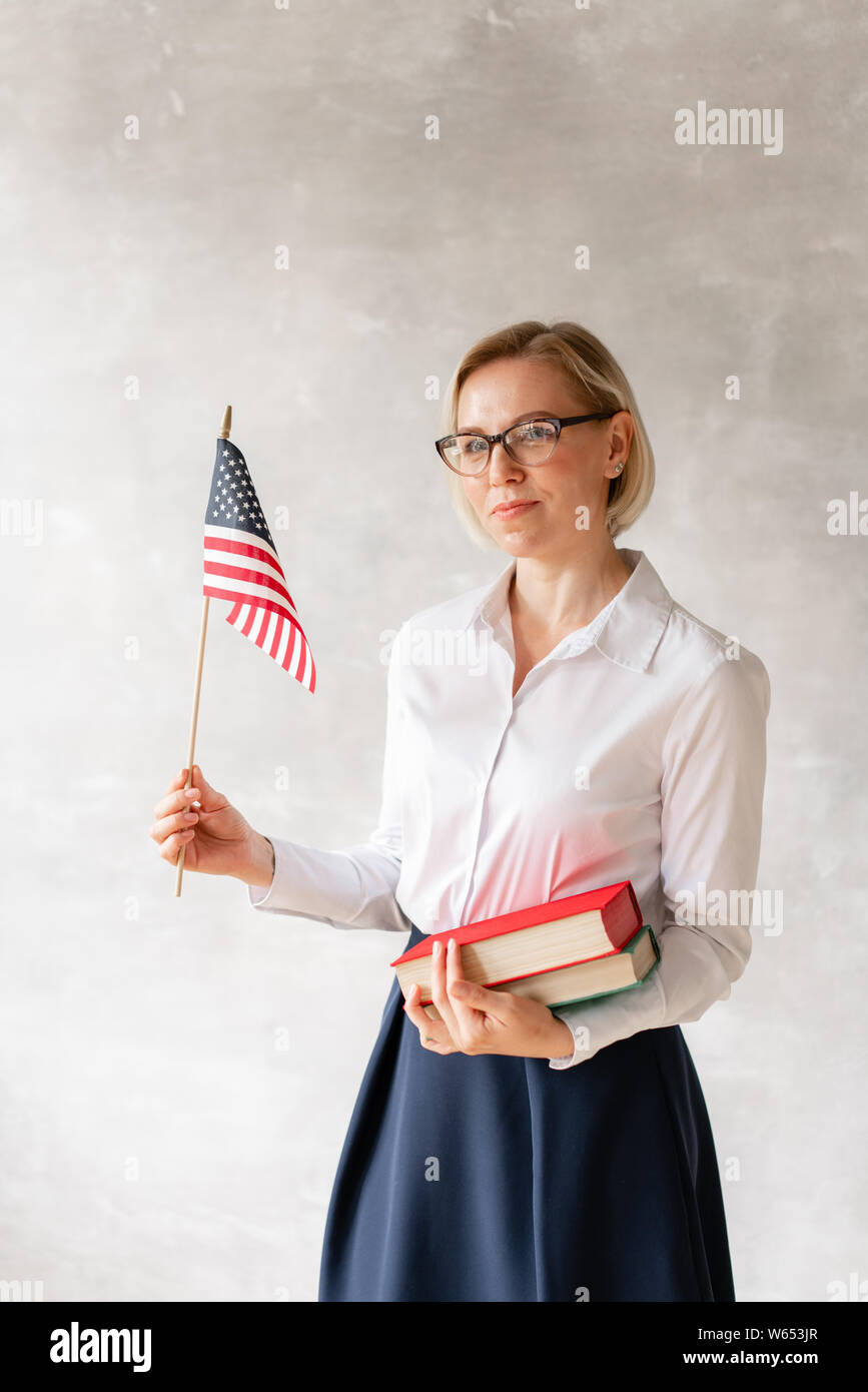Affascinante insegnante camicetta da indossare gonna e detiene due libri e bandiera nelle sue mani Foto Stock