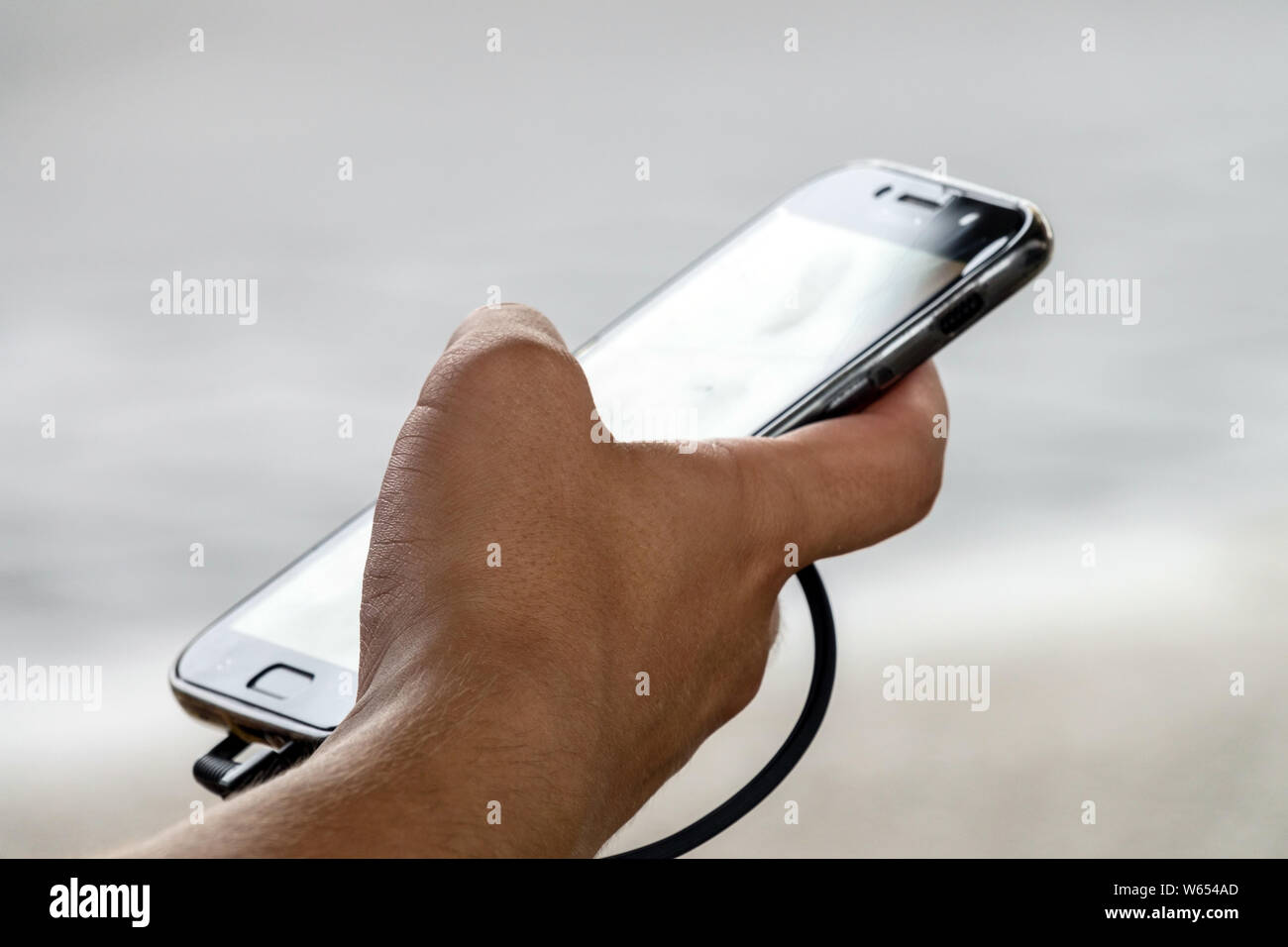 Un uomo che usa il telefono cellulare con una mano, primo piano Foto Stock