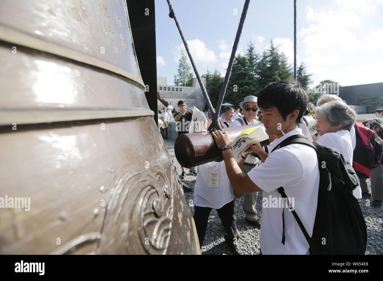 I delegati provenienti da Giappone colpire una campana di cordoglio per le vittime del massacro di Nanjing durante un assembly per contrassegnare la 73th anniversario del Giappone del uncondition Foto Stock