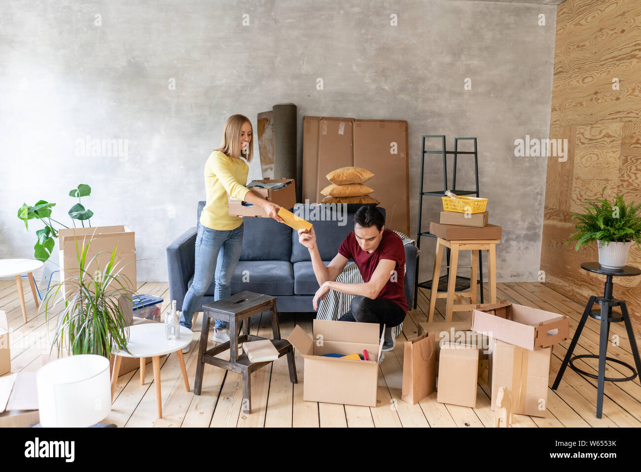 Sorridenti giovane che si muove in una nuova casa e disimballaggio di cartoni, scatole di dislocazione e ristrutturazione concept Foto Stock