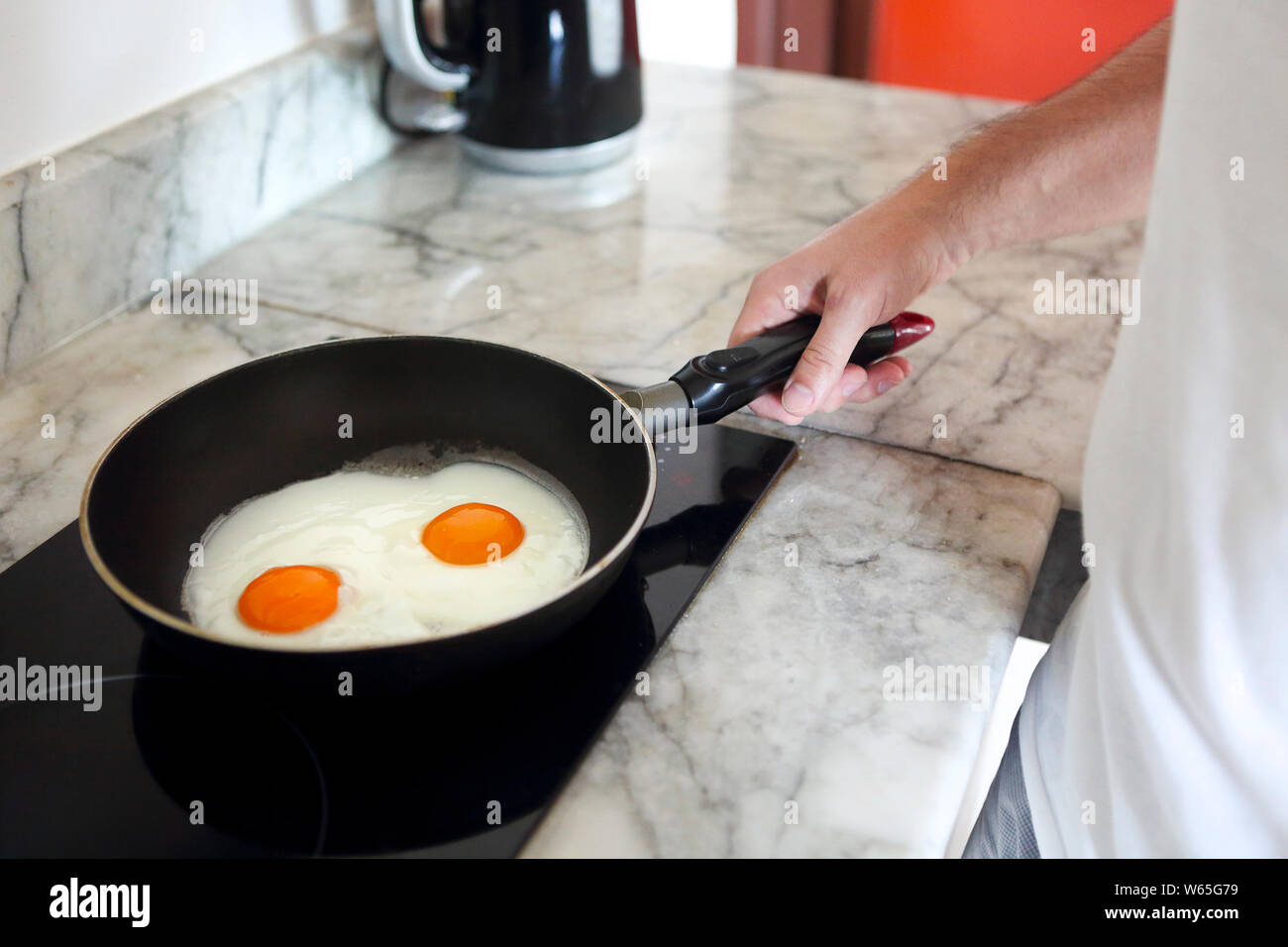 Immagine ritagliata dell uomo per la cottura delle uova strapazzate in padella in cucina Foto Stock