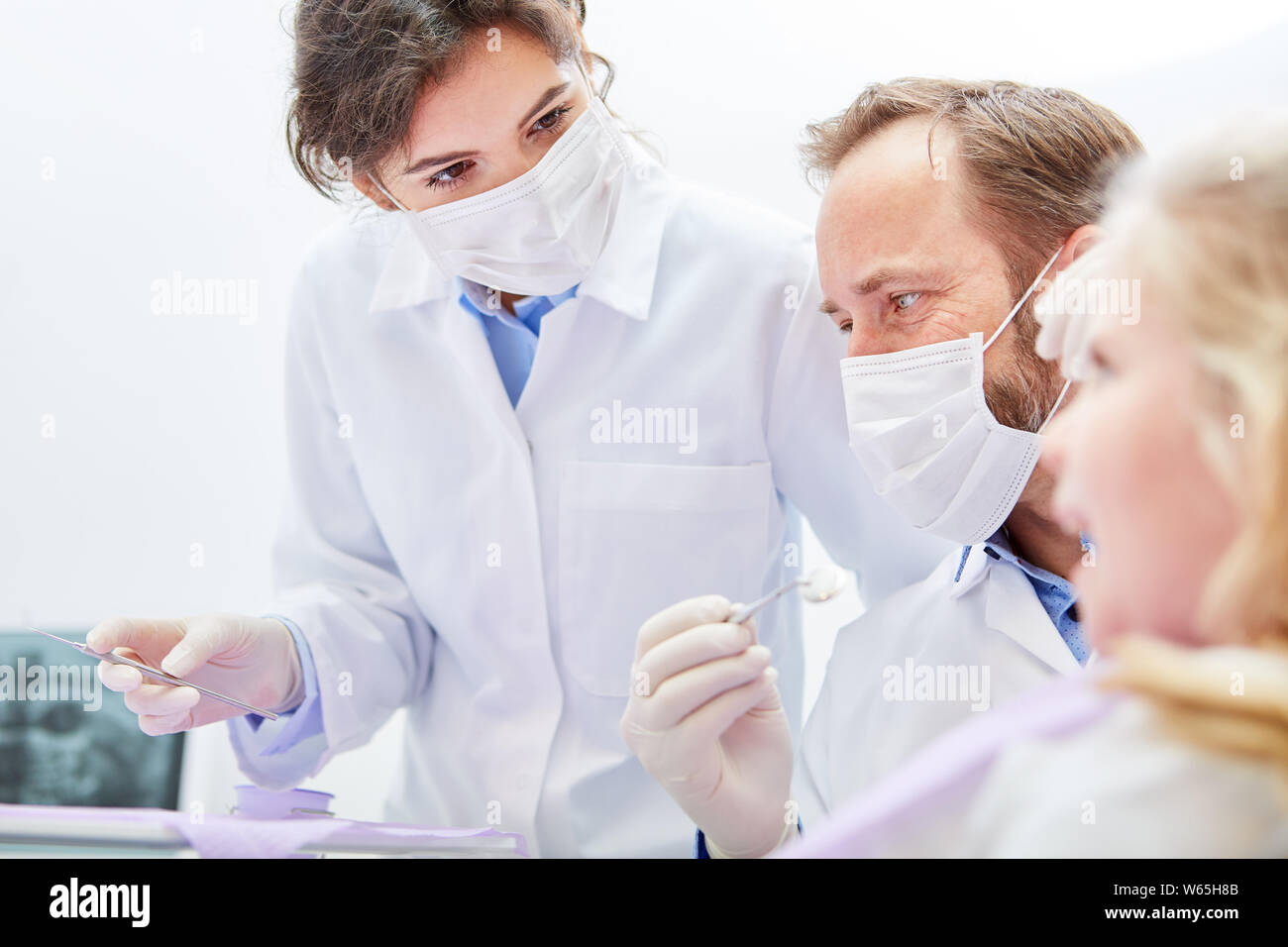 Dentista e assistente trattare insieme un bambino come un paziente nella clinica dentale Foto Stock