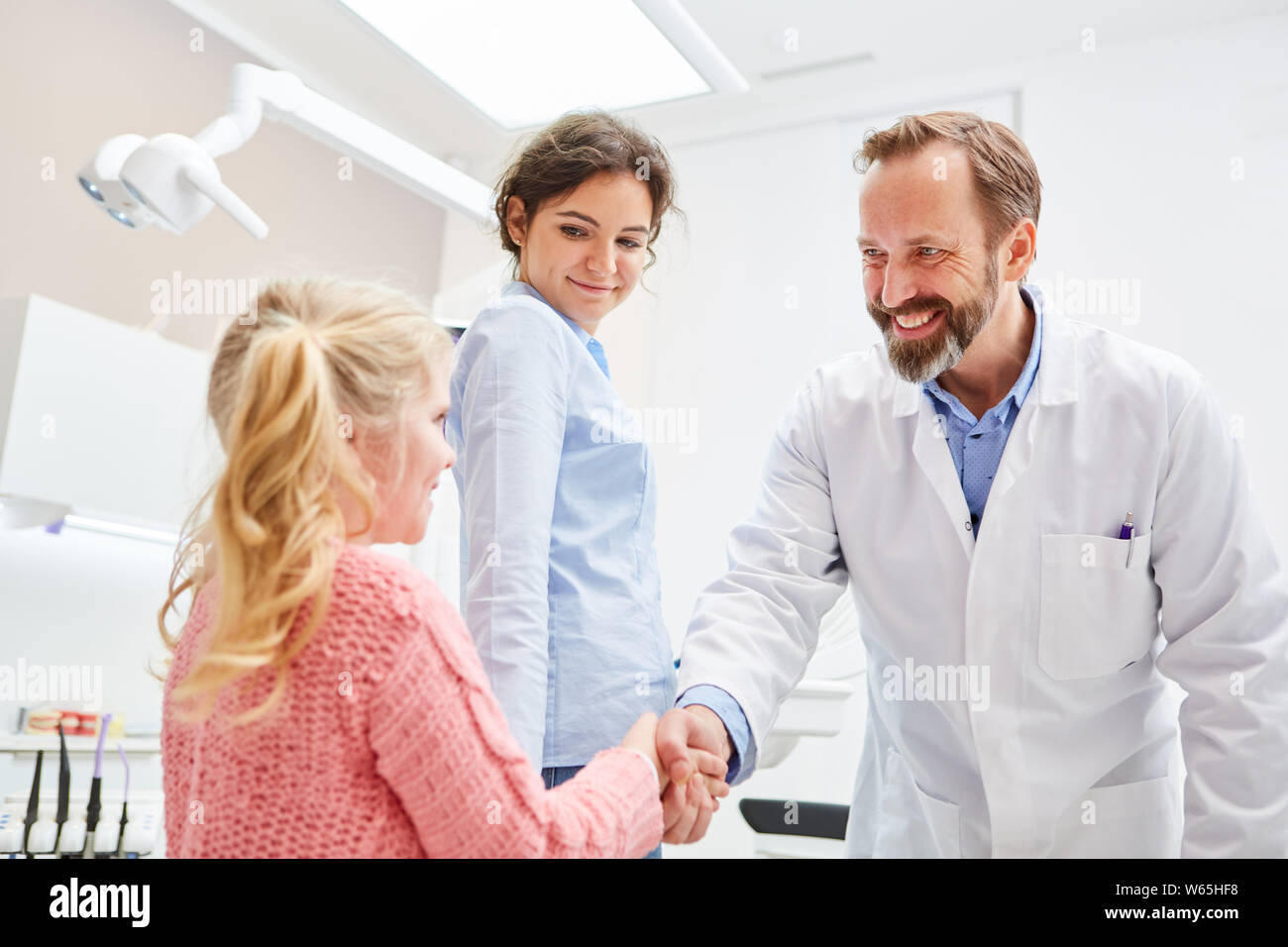 Dentista accoglie ansiosi ragazza con handshake prima del trattamento in studio dentistico Foto Stock