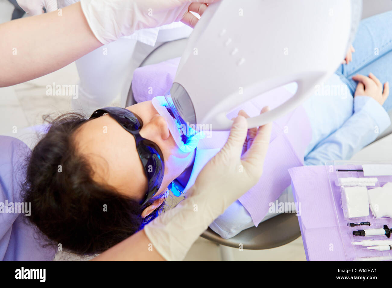 Cosmetici professionali per lo sbiancamento dei denti con LED blu nello studio dentistico Foto Stock