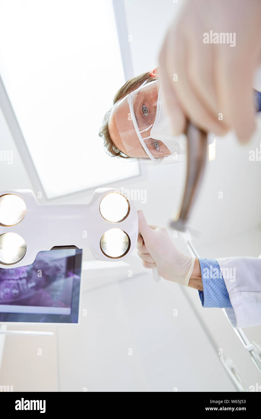 Dentista o chirurgo con visiera ad una chirurgia dentaria nella clinica dentale o chirurgia maxillo facciale Foto Stock