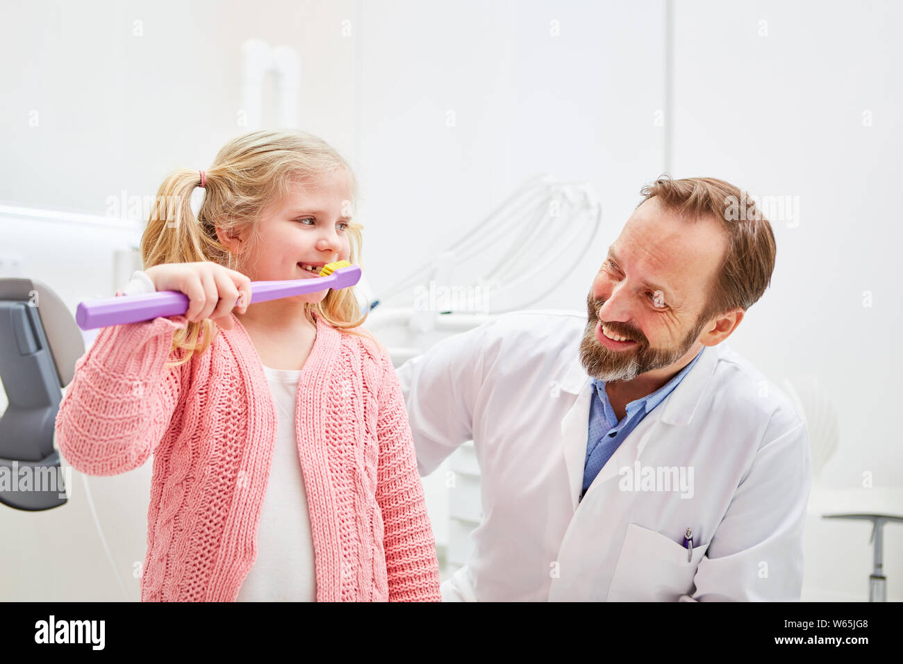 Dentista pediatrico spiega a una ragazza la corretta pulizia dei denti come una precauzione per la salute dentale Foto Stock