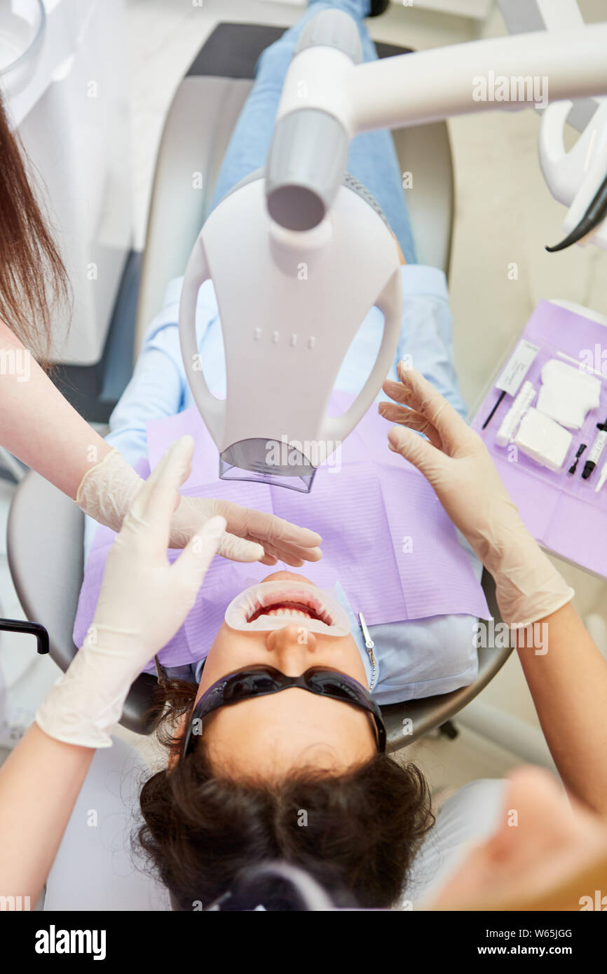 Il team medico e paziente in cosmetica per lo sbiancamento dei denti in uno studio dentistico Foto Stock