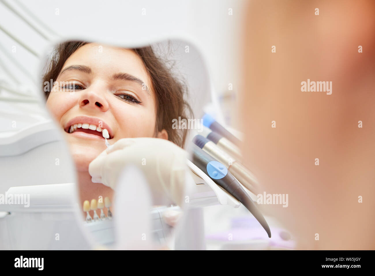 Giovane donna in cosmetici sbiancamento dei denti o sbiancante criticamente guarda nello specchio Foto Stock