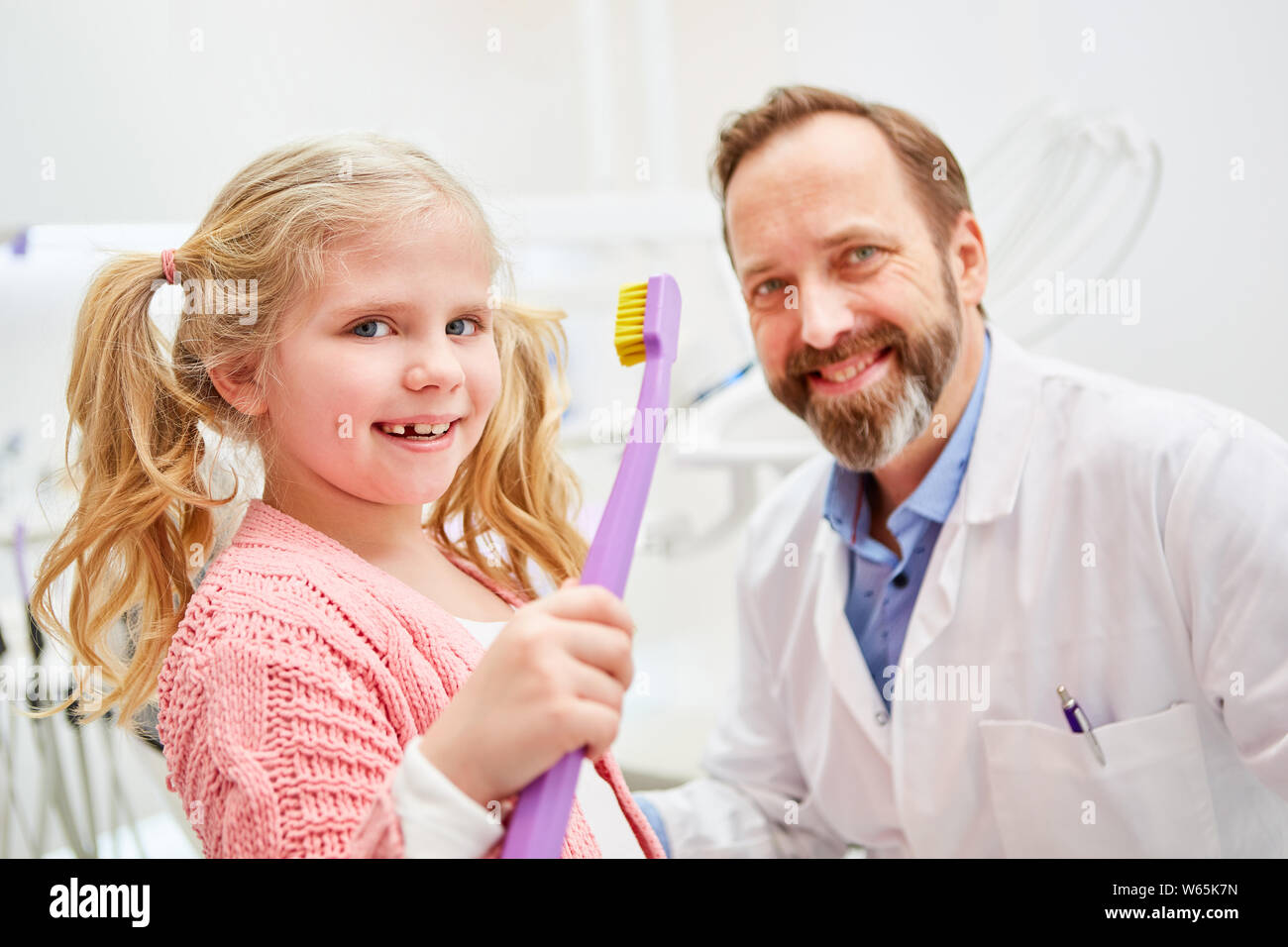 Ragazza sorridente al dentista pediatrico con spazzolino gigante Foto Stock