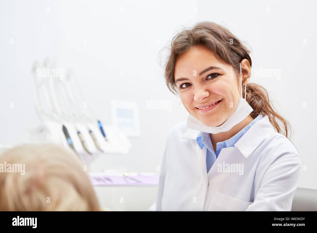 Sorridente giovane donna come un assistente dentale o il dentista in uno studio dentistico Foto Stock